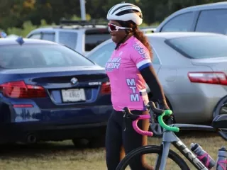 Female cyclist in pink shirt and helmet beside her bicycle