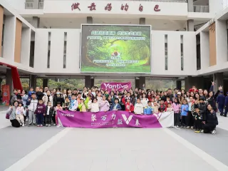 Large group of adults and children gathered outside a building, holding a Vantive banner.