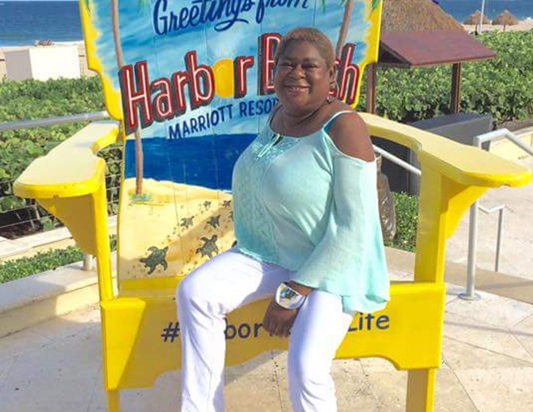 Woman sitting on beach chair with sign 'Harbor Beach' in the background