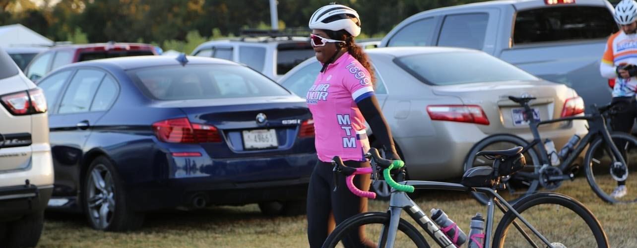 Female cyclist in pink shirt and helmet beside her bicycle
