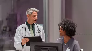 Two healthcare professionals discussing in front of monitor