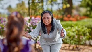 Woman reaching arms out to young girl for a hug