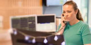 Women in green scrubs sits at a desk on the phone