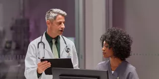 Two healthcare professionals discussing in front of monitor