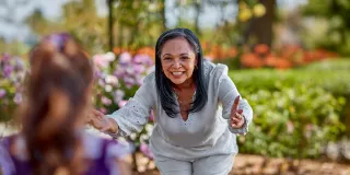 Woman reaching arms out to young girl for a hug